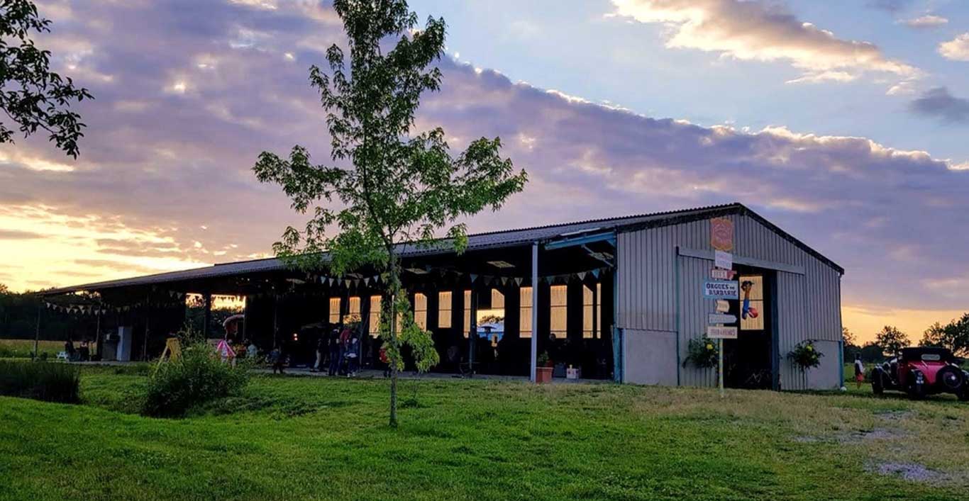 le soleil se couche sur des gens qui s'amusent sous un grand hangar ouvert